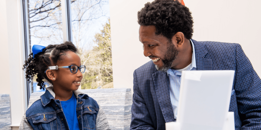 African American father smiling at his daughter as they're at an eye appointment