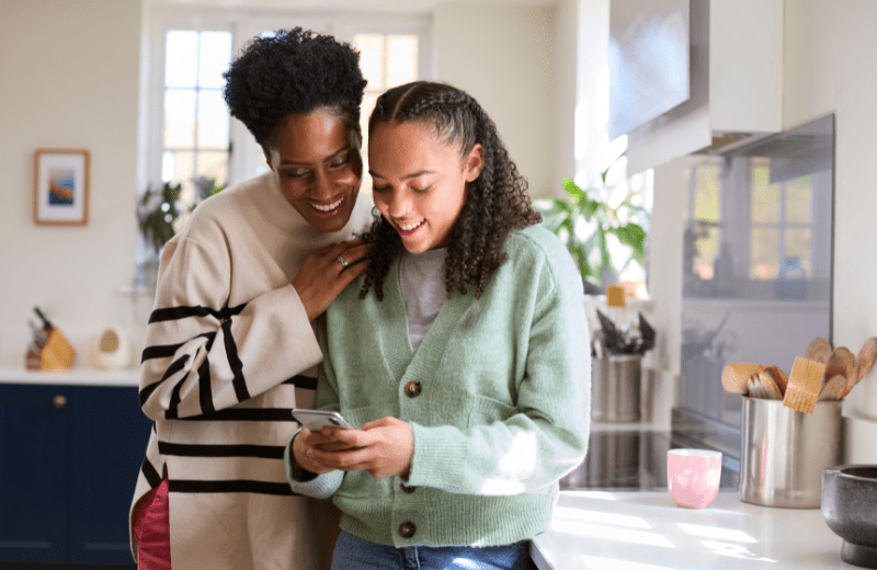 Mother and teen daughter looking at phone together